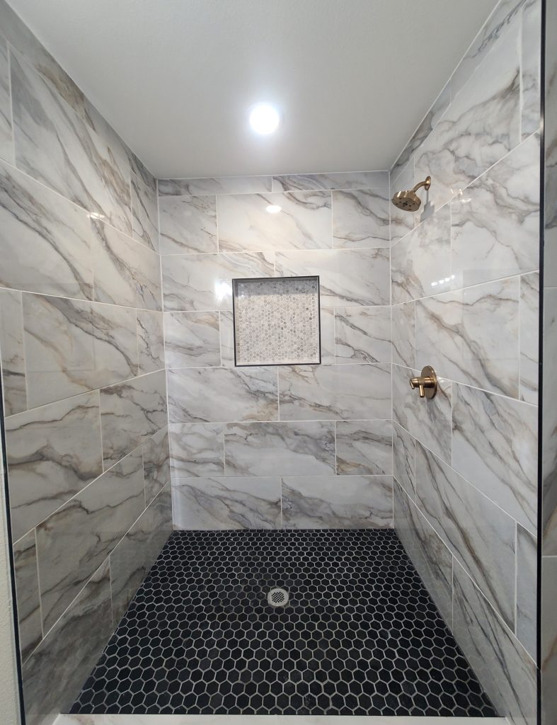 Modern standing shower with black hexagon tile and gold finishes in Denison, TX