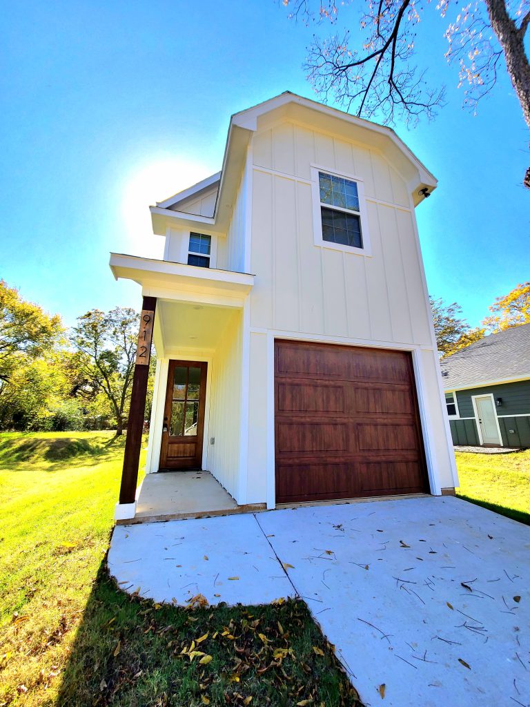 Newly built yellow two-story home in Denison, Texas with a single car garage