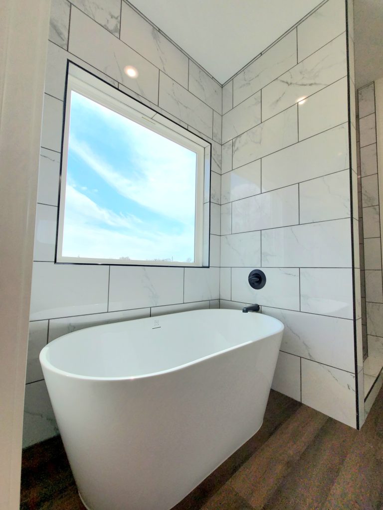 Bathtub with black fixtures and large scenic window in Tom Bean, Texas