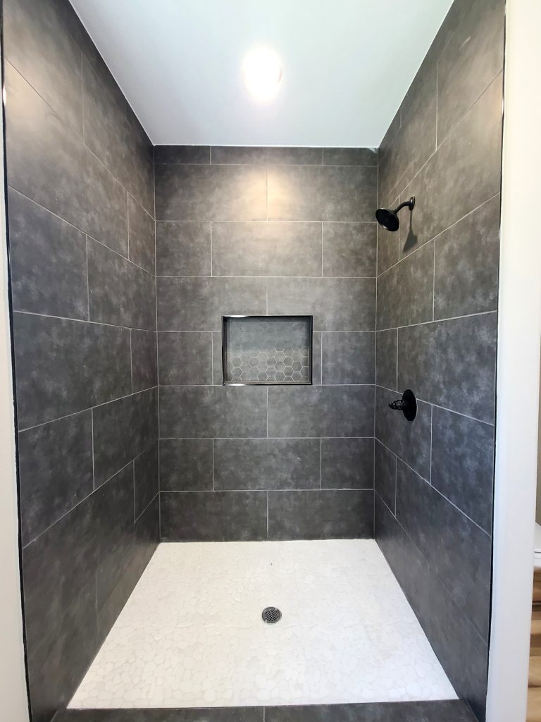 Large dark tile with light stone flooring and black fixtures built in Tom Bean, TX